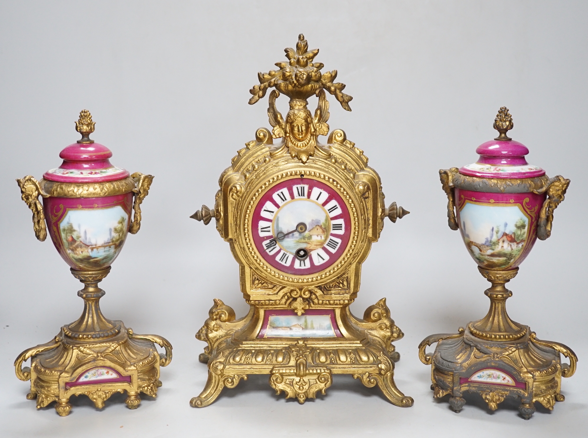 A 19th century porcelain mounted gilt spelter clock garniture, hand painted with landscapes, 30cm high